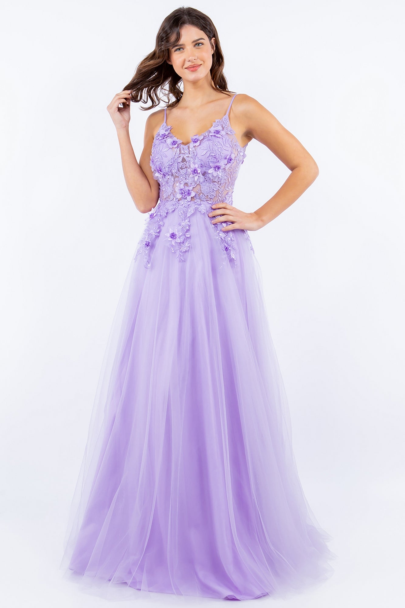 A woman stands smiling against a plain white background, wearing the Sheer-Bodice Long A-Line Prom Ball Gown 8038J with 3D floral accents and a flowing tulle skirt.